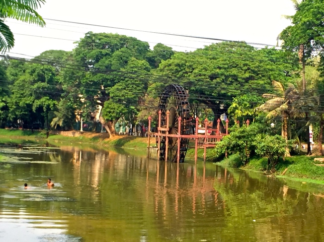 Water Wheel over the Siem Reap River with swimmers nearby